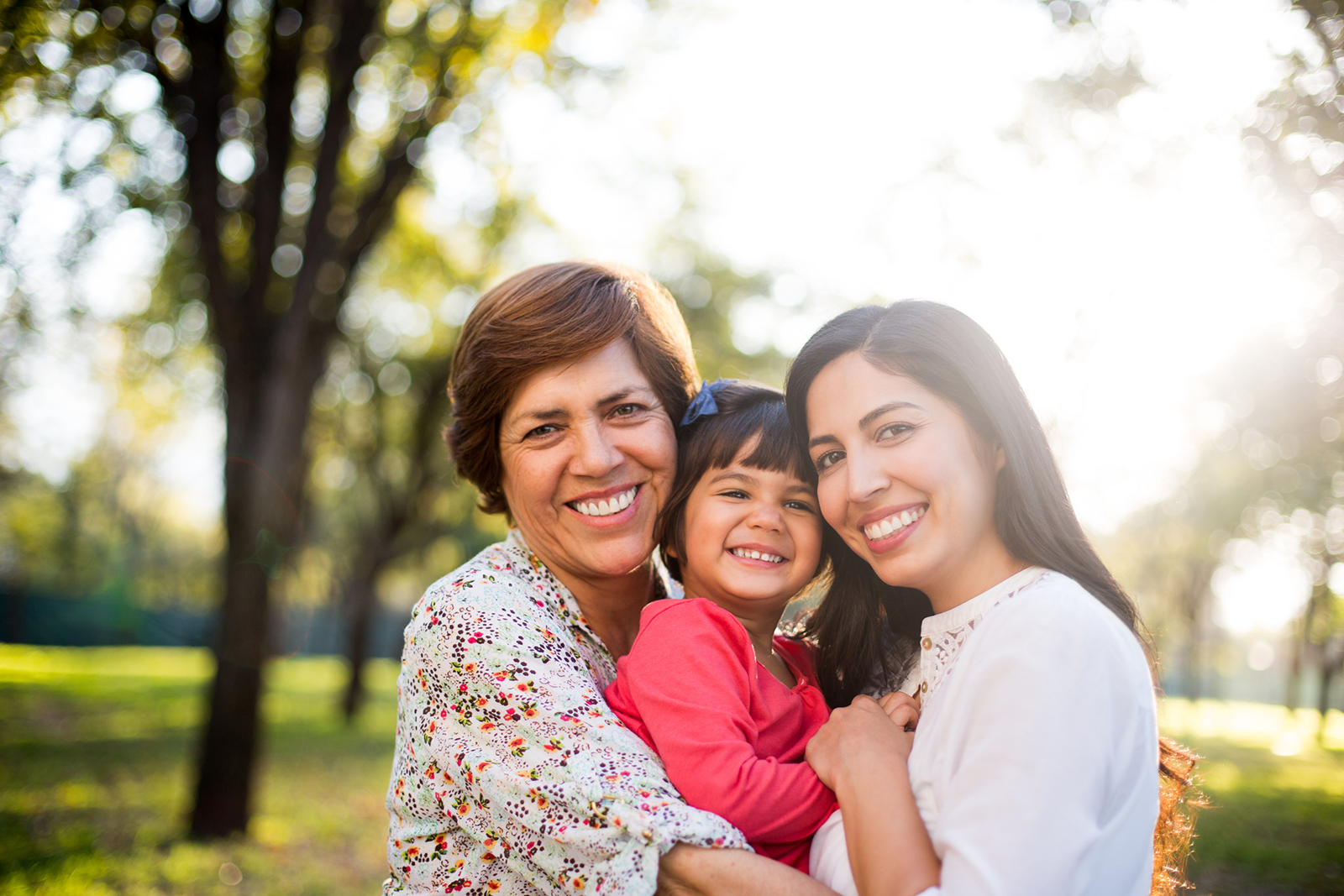 Grand-mère, mère et jeune fille s'embrassant dehors.