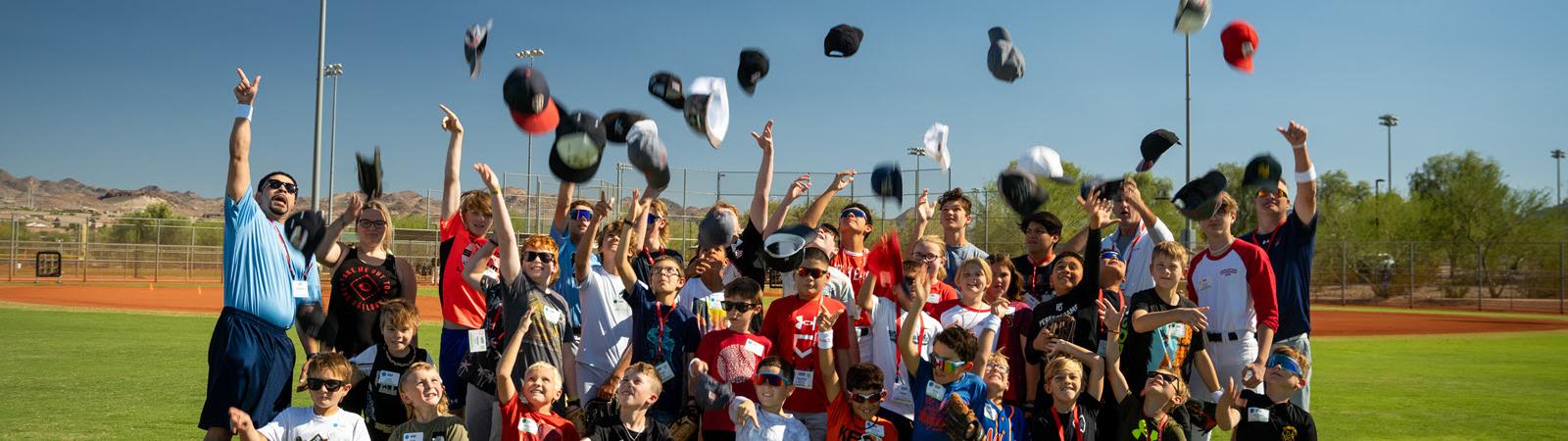 Baseball participants and coaches throw their caps in the air.
